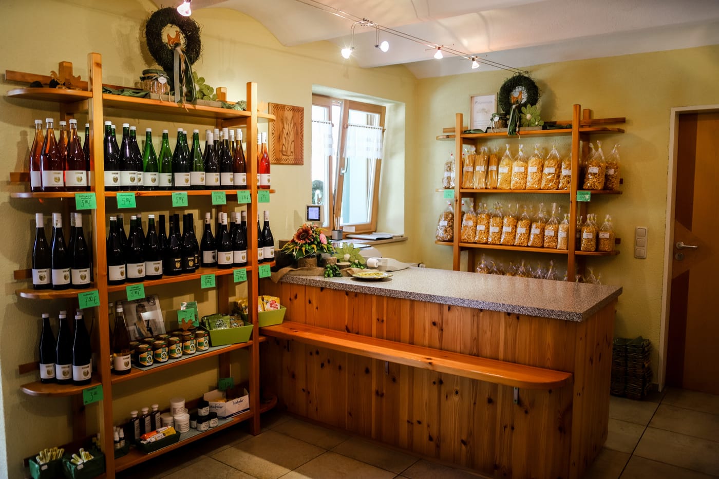 Verkaufstheke im Hofladen mit Weinregal und Produkten regionaler Betriebe